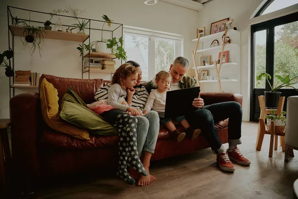 Young family with daughter watching video on laptop while relaxing at home — Stock Photo, Image