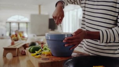 Mutfakta yemek hazırlayan, yumurta çırpan ve sağlıklı bir kahvaltı hazırlamak için tavaya sebzeyle dolduran bir kadının yakın çekimi.