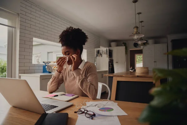 若い女性起業家は家から仕事中にラップトップを使用している間に鼻を吹いて座っている — ストック写真