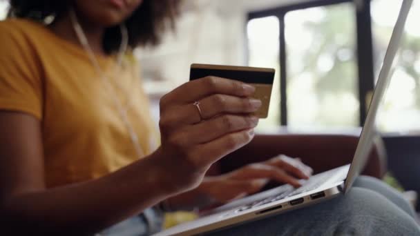 Primer plano de una mujer afroamericana sosteniendo una tarjeta de crédito en su mano haciendo banca por Internet usando un portátil — Vídeos de Stock