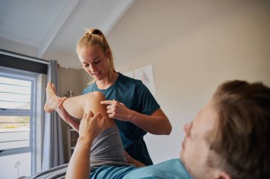 Fizyoterapist diz ağrısı olan hastaya yardım ediyor.