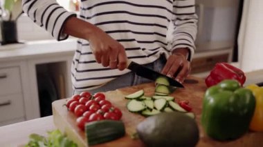 Mutfak masasının yanında duran, salata için bıçakla taze kabak kesen bir kadın.