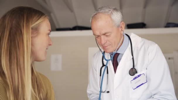 Senior male doctor being measuring and checking young female patient blood pressure to symptom diagnosis illness in clinic — Stock Video