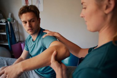 Kadın doktorla el yaralanması için fizyoterapi gören genç bir adam.