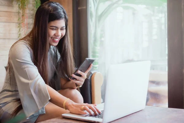 Akıllı telefon ve dizüstü bilgisayar kullanan mutlu bir kadın.