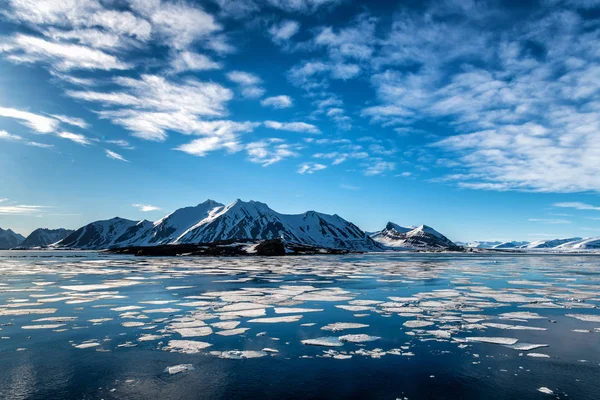 Білий лід пливе в блакитному океані з білими хмарами — стокове фото