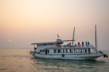 Halong Bay, Vietnam - 24 Aralık 2013: Halong Körfezi'nde gün batımı ile ilgili birkaç kişiyle gezinen turist teknesi.