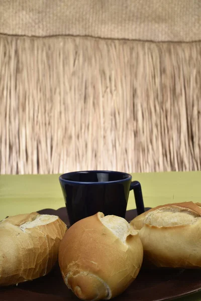 Pão francês, em prato com xícara preta no fundo — Fotografia de Stock