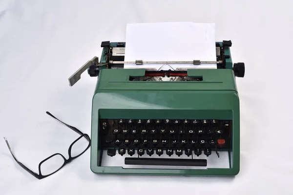 Antik-Schreibmaschine im Retro-Look mit Papier und Brille daneben auf weiß — Stockfoto