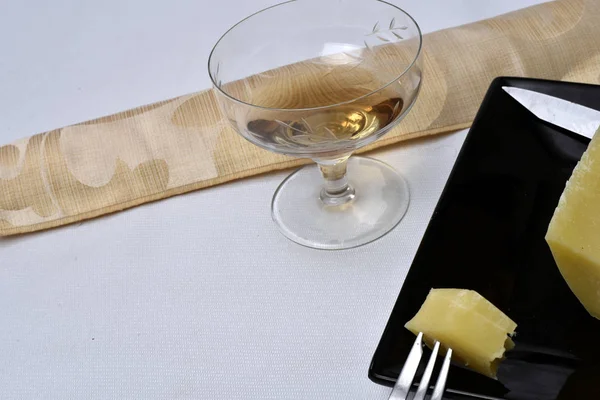 Стакан алкогольного напитка с сыром на столе на белом бэкге — стоковое фото