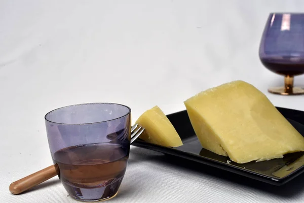 Стакан алкогольного напитка с сыром на столе на белом бэкге — стоковое фото