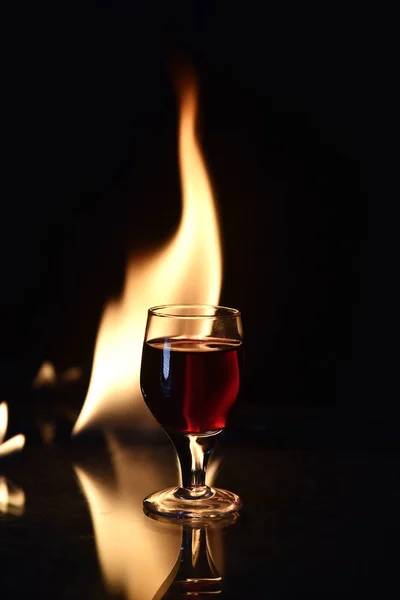 Czerwony napój z ogniem z tyłu i refleksji na czarnym tle — Zdjęcie stockowe