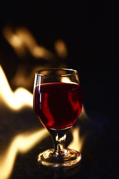 Rood drankje met vuur achter en reflectie op zwarte achtergrond — Stockfoto