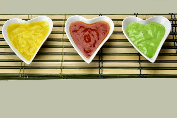 Миска білої форми серця з різнокольоровими соусами на пробці та бамбуку м — стокове фото