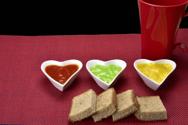 Миска білої форми серця з соусами з нарізаними хлібами на червоному фоні — стокове фото