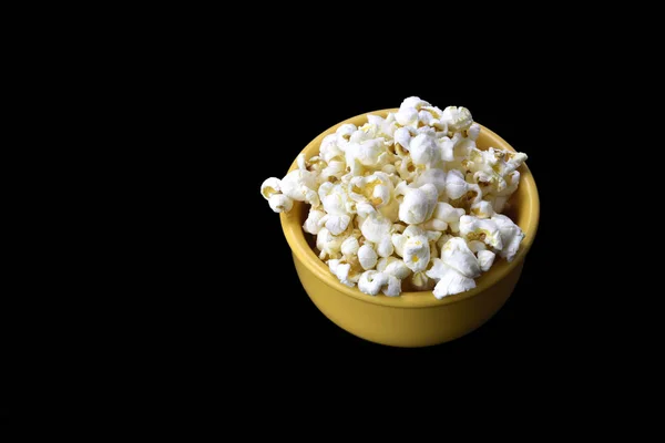 Popcorn in gelber Schüssel auf schwarzem Hintergrund — Stockfoto