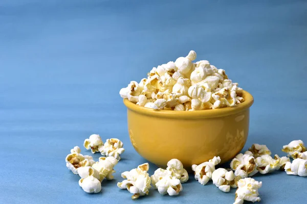 Popcorn in Schale mit rosa Boden mit Mais daneben auf blauem Ba — Stockfoto