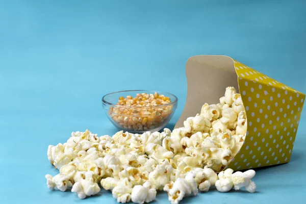 Popcorn fällt aus Papierverpackung mit blauem Hintergrund — Stockfoto