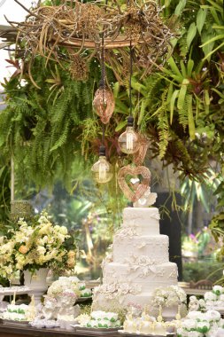 Çiçeklerle süslenmiş beyaz pasta bayram masasında duruyor.