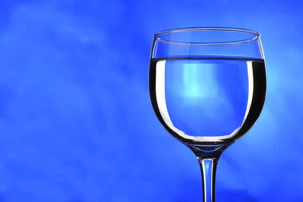 Doorschijnende drank in glas met blauwe achtergrond — Stockfoto