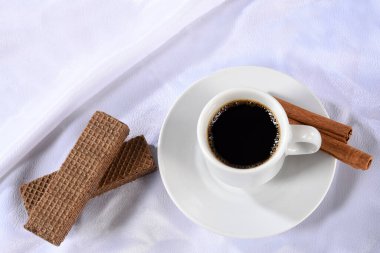 Beyaz kumaş üzerine izole edilmiş kahve ve kurabiyeli beyaz porselen bardak.