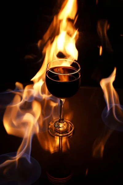 Cam Masanın Üzerinde Kırmızı Şarap Bardağı Siyah Arka Planda Ateş — Stok fotoğraf