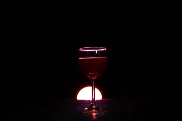 ガラスのテーブルの上の赤ワインのガラスが黒い背景に火をつけてロマンチックな写真 — ストック写真