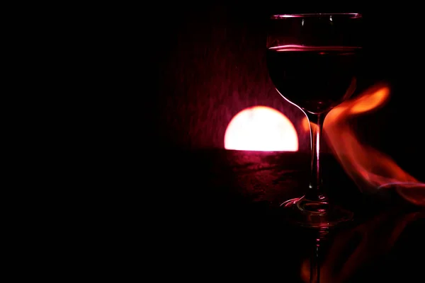 Bicchiere Vino Rosso Tavolo Vetro Con Fuoco Intorno Sfondo Nero — Foto Stock