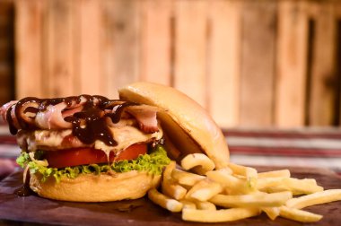 Açık brioche krem peynirli hamburger ve bulanık arka planda, masada domuz pastırması sosu.