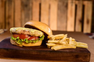 Açık brioche krem peynirli hamburger ve bulanık arka planda, masada domuz pastırması sosu.