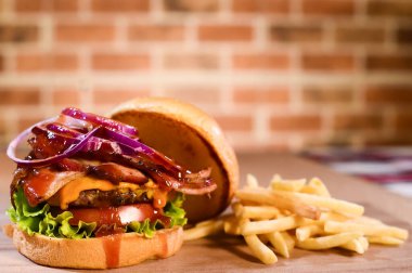 Açık brioche krem peynirli hamburger ve bulanık arka planda, masada domuz pastırması sosu.