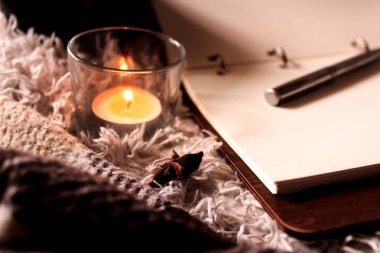 Hygge tarzı. Sıcak battaniye, yanan mumlar, notalar için kitap. vintage tarzı, natürmort.