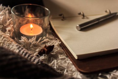 Hygge tarzı. Sıcak battaniye, yanan mumlar, notalar için kitap. vintage tarzı, natürmort.