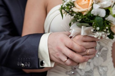 Bej portakal gül düğün buketi. Gelinin wirst ihalesini tutan damat elinin yakın çekimi