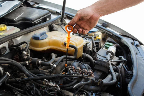 A man independently checks the oil level in the car. DIY car service