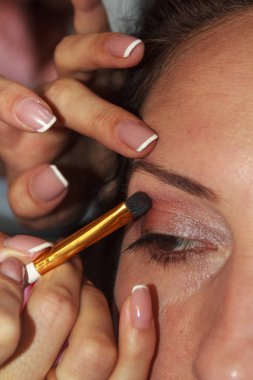 Kız makyaj yapıyor. üst göz kapağına makyaj fırçası ile soluk pembe göz farı uygulama