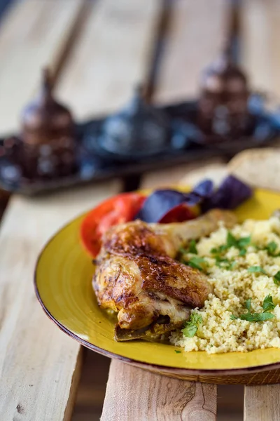 Roasted chicken leg with bulgur and herbs served with bread and coffee on a wooden background