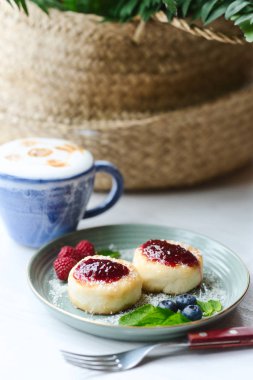 Ahududu reçeli, çilek ve nane yaprakları ile Cheesecakes latte bir fincan ile servis