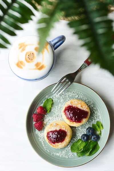 Ahududu reçeli, çilek ve nane yaprakları ile Cheesecakes latte bir fincan ile servis