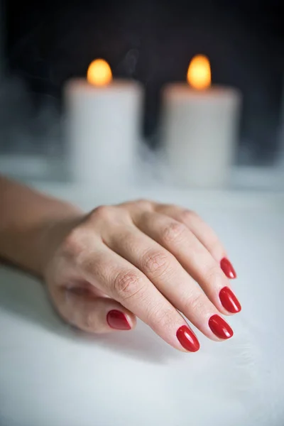 Red manicure, candles and smoke. Salon manicure result