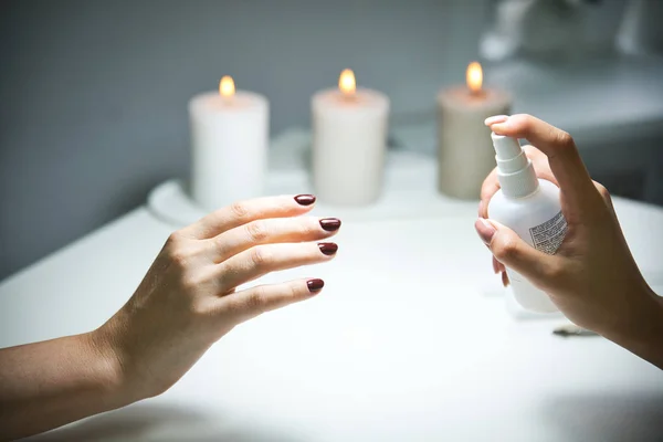 Arka planda yanan mumlarla dezenfekte edilmiş manikür spreyi.