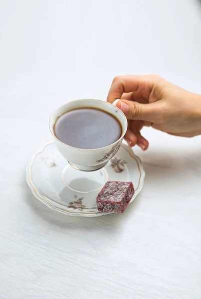 Taça de chá de porcelana branca em um fundo branco em mãos de mulheres — Fotografia de Stock