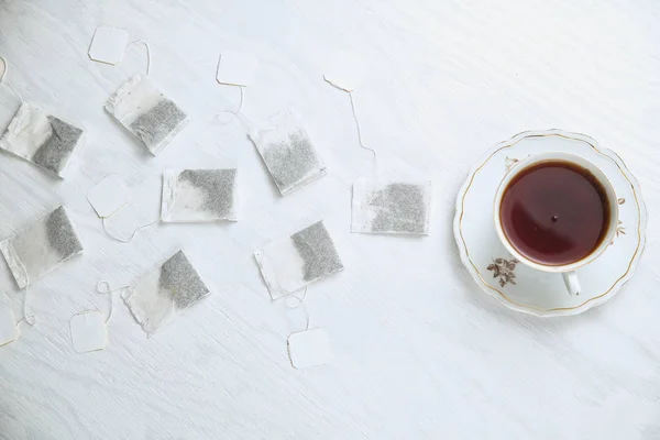Theezakjes lijken achter een porseleinen kopje thee aan te lopen — Stockfoto