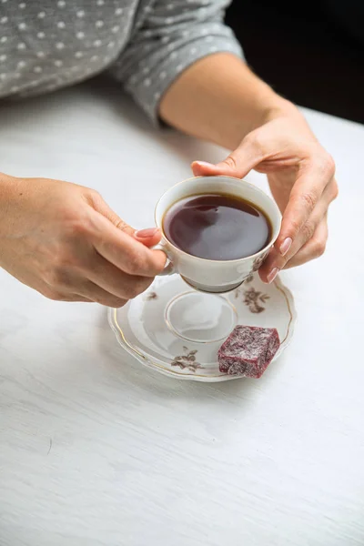 Taça de chá de porcelana branca em um fundo branco em mãos de mulheres — Fotografia de Stock