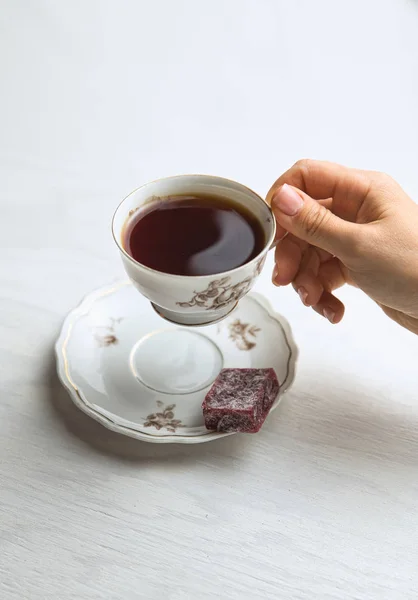 Taça de chá de porcelana branca em um fundo branco em mãos de mulheres — Fotografia de Stock