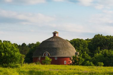 Çayır ve güzel gökyüzü ile yuvarlak kırmızı ahır. Kewanee, Illinois, ABD