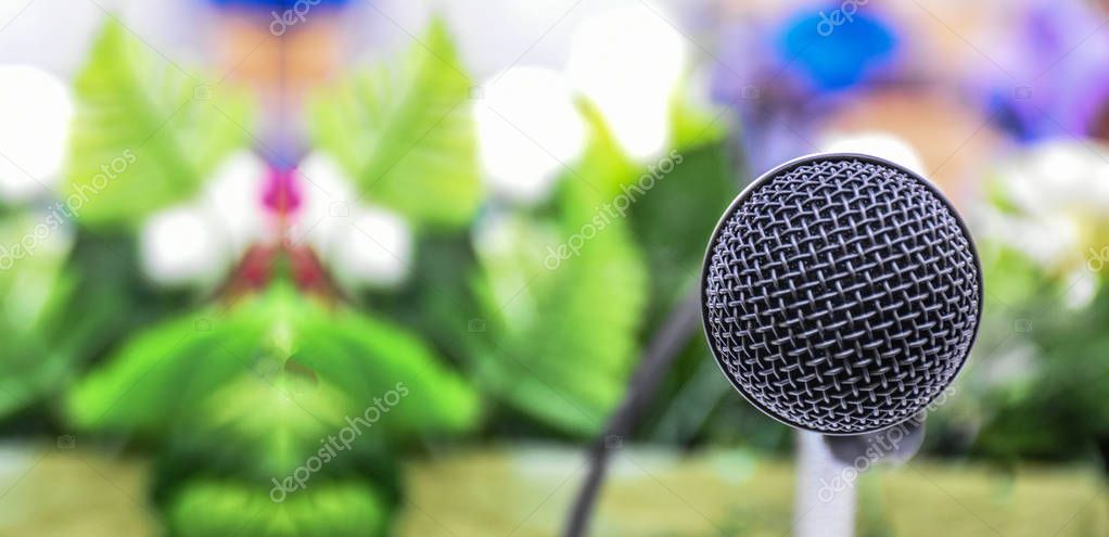 microphone on the table in seminar hall with green tone and audience  for background and space  