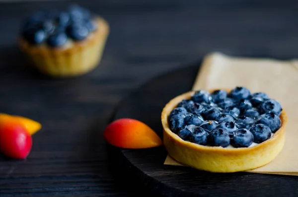 Yaban mersinli tart ve koyu ahşap masada krema, yakın plan.