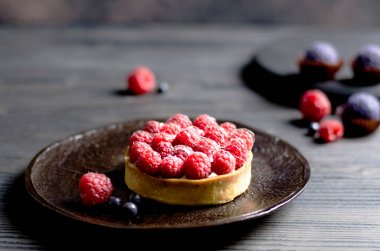 Ahududu turtası, ahududu üzerine odaklanmış, koyu ahşap masa.