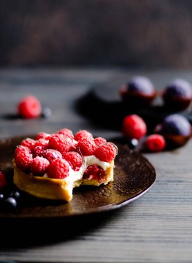 Kemirilmiş ahudududulu pastayı dikey görüntüye yaklaştır, böğürtlenlere odaklan, mavi şekerlere odaklan